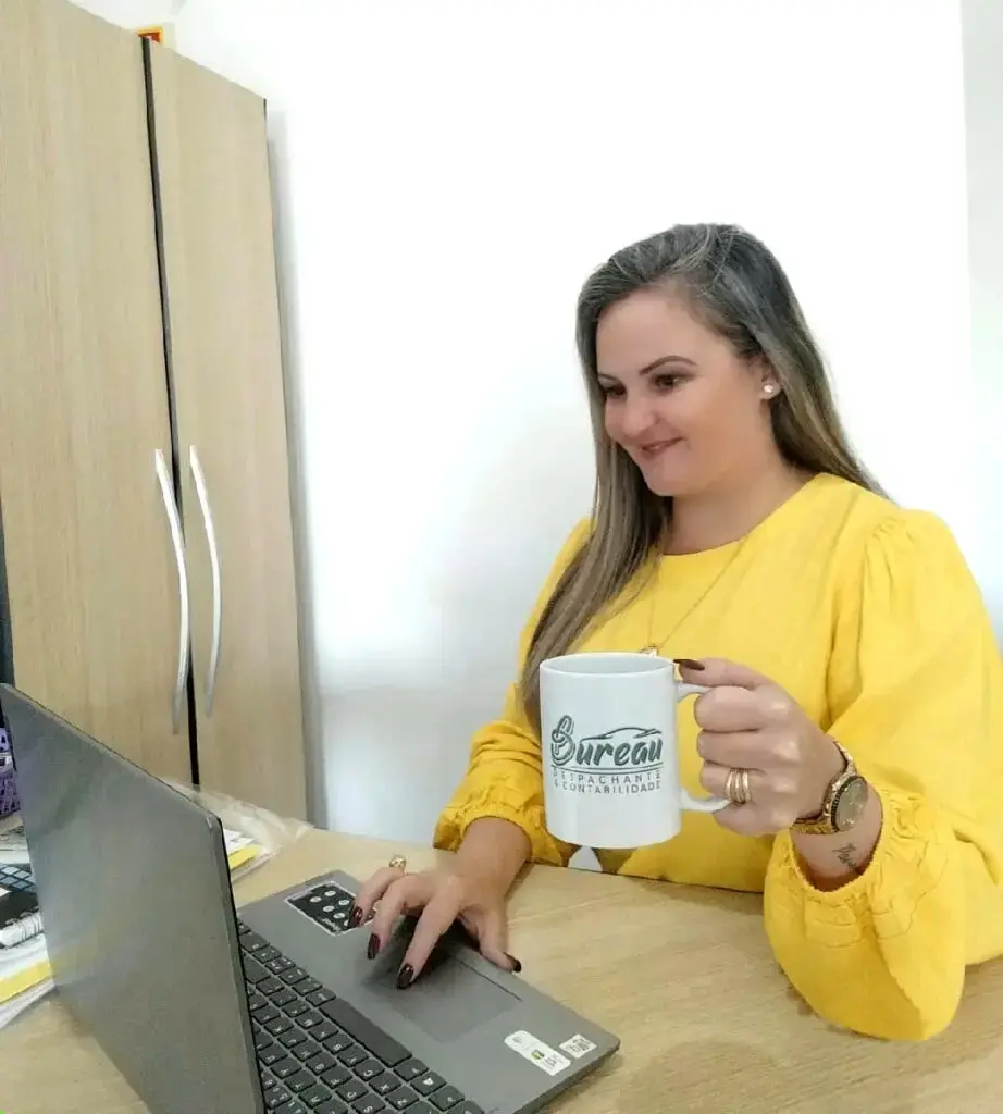 Profissional da Bureau Contabilidade trabalhando no notebook, com uma caneca da marca sobre a mesa