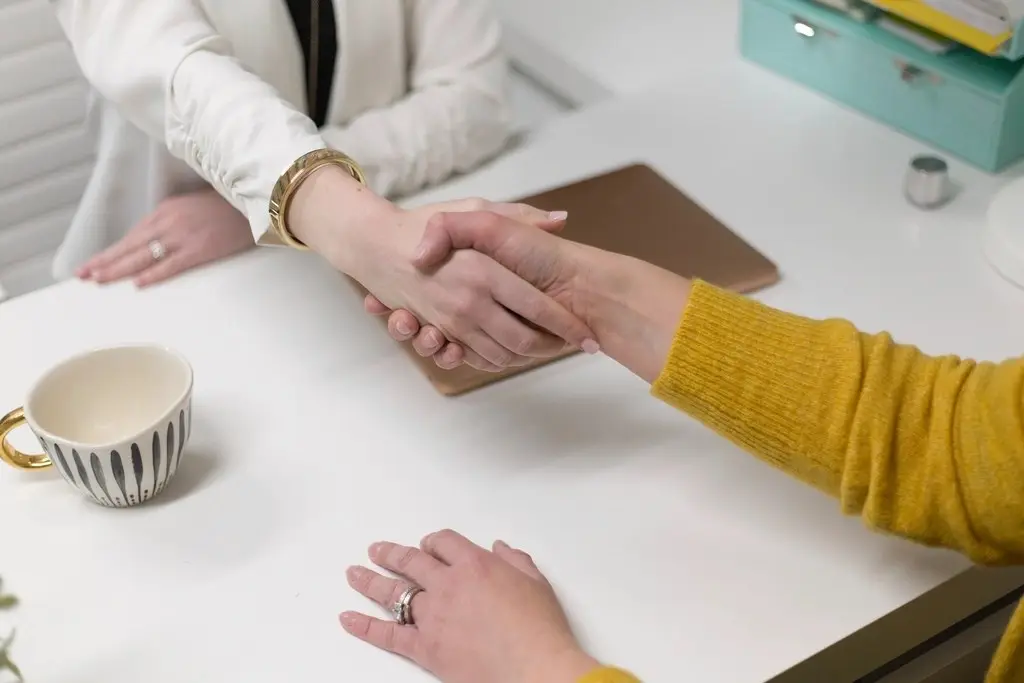 Duas pessoas apertando as mãos sobre uma mesa de escritório